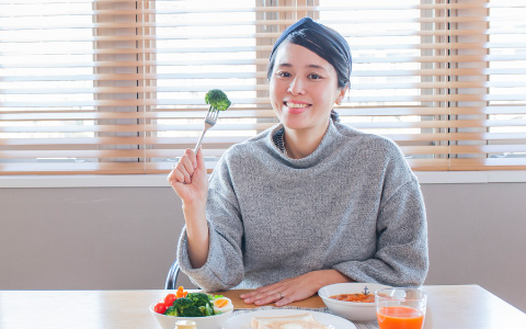 野菜を食べようとして微笑んでいる女性